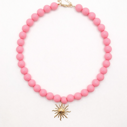 Zuurstok roze kralenketting met goudkleurige zon bedel in Ibiza style van Casa Jadel