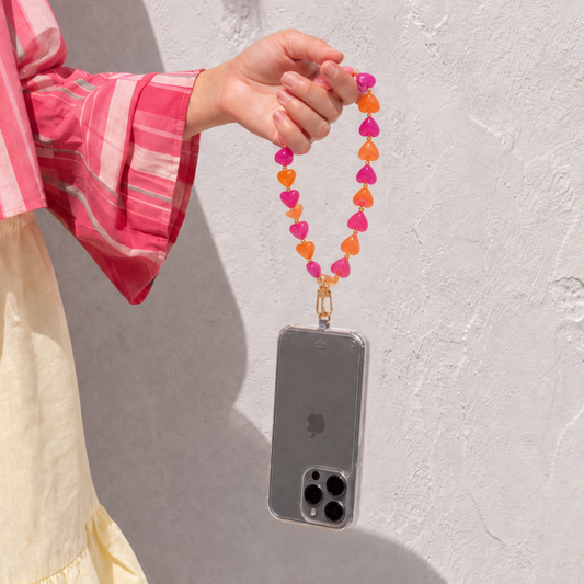 Model houdt telefoon vast met roze en oranje hartjes telefoonkoord van Casa Jadel