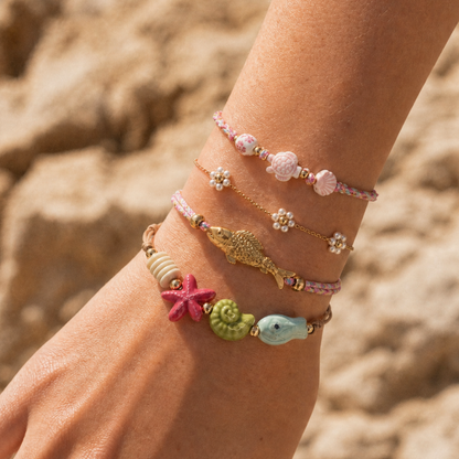 Model draagt roze zeedieren armbanden met gouden vis en parelbloemen van Casa Jadel