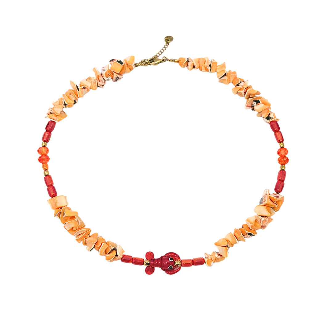 Schelpen kralenketting in oranje tinten met rode kreeft bedel en goudkleurige details