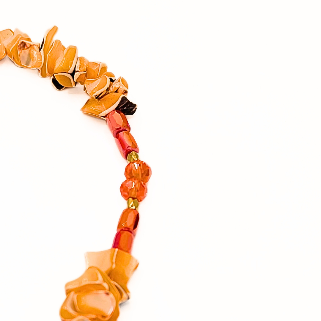 Detail van schelpen kralenketting met rode   en oranje kralen.