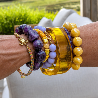 arm met gele en paarse armbanden 
