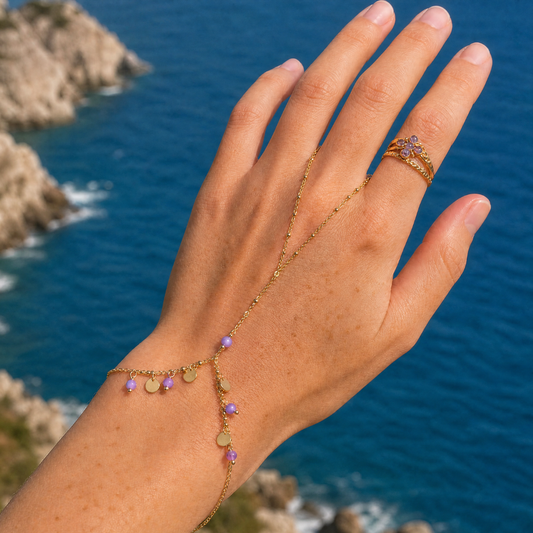 Gouden handchain armband met ring, paarse kraaltjes en gouden bedeltjes gedragen