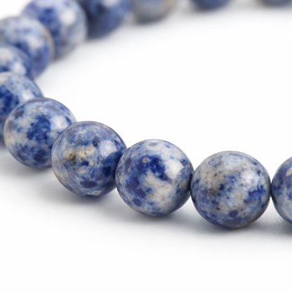 inzoom Sodaliet natuursteen kralenarmband met diepblauwe kralen en witte aders op witte achtergrond.
