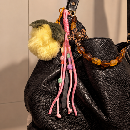 Zwarte tas met gele pompon, amber chunky kralen met bloem en roze slierten tashangers