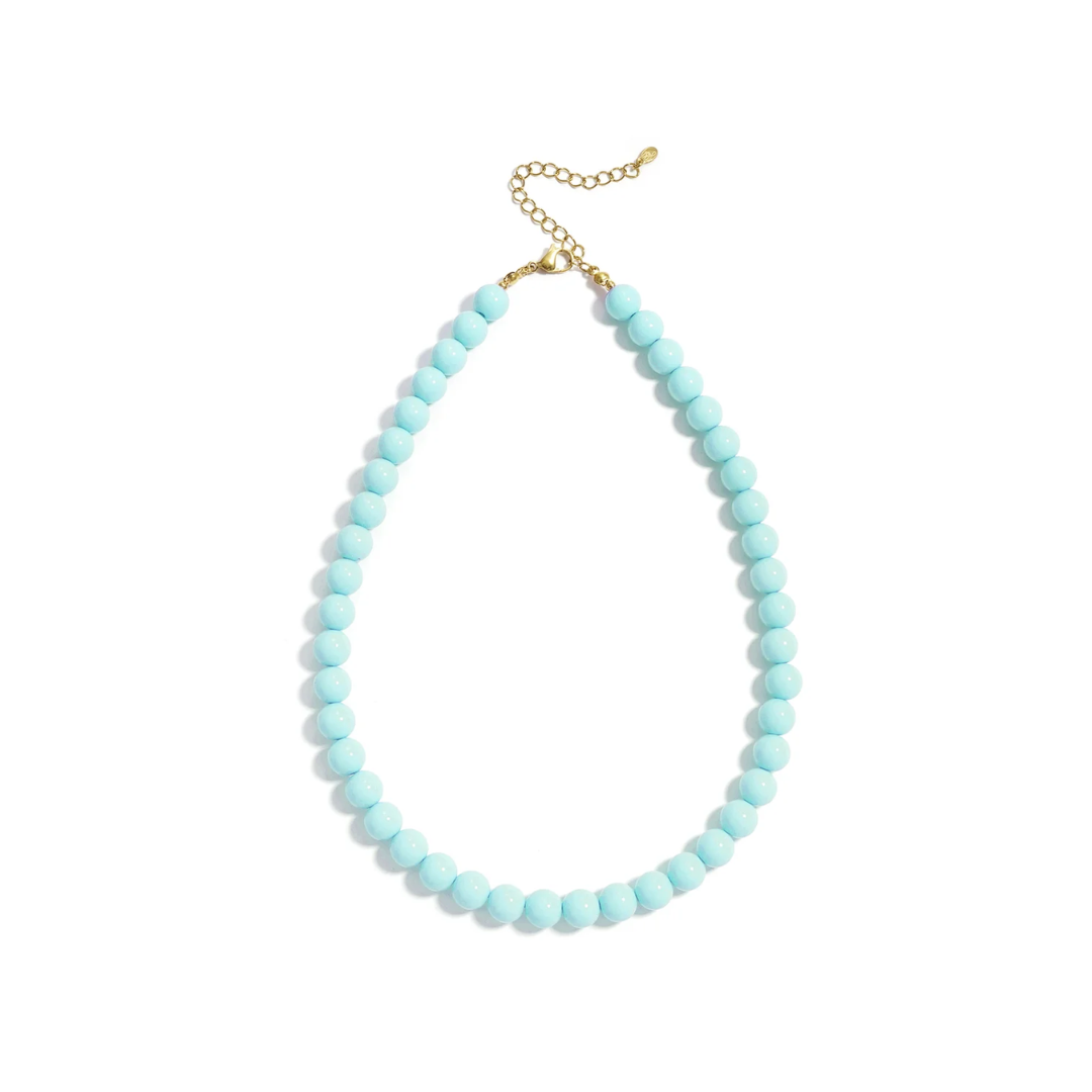 Turquoise kralenketting Olivia met ronde glaskralen en goudkleurige stainless steel sluiting van Casa Jadel op een witte achtergrond.