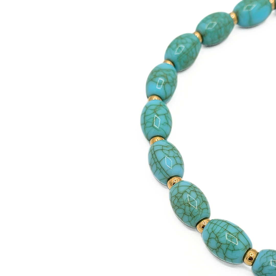 Detail van ovale turquoise kralen met marmerstructuur en goudkleurige tussenkralen