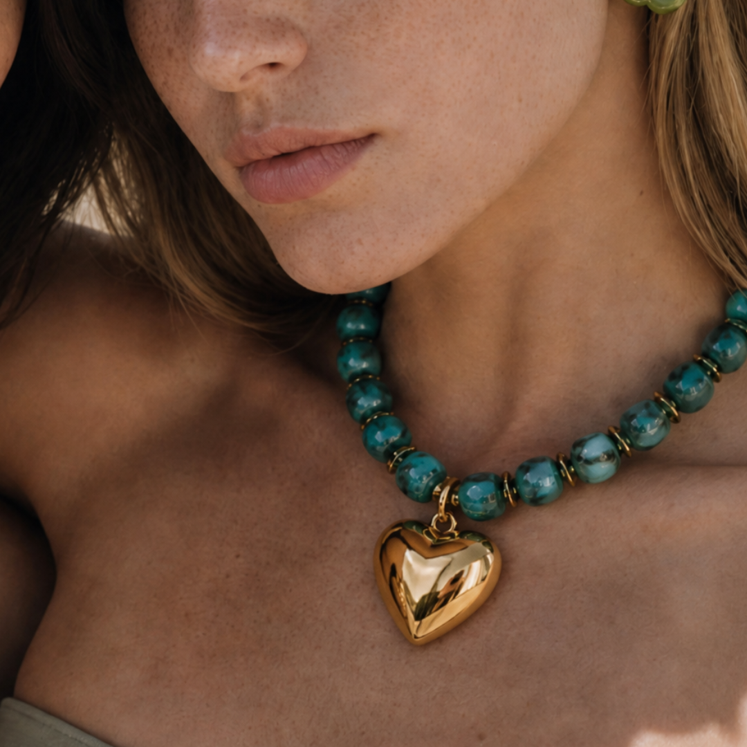 Model draagt een turquoise kralenketting met goudkleurige hart bedel van Casa Jadel