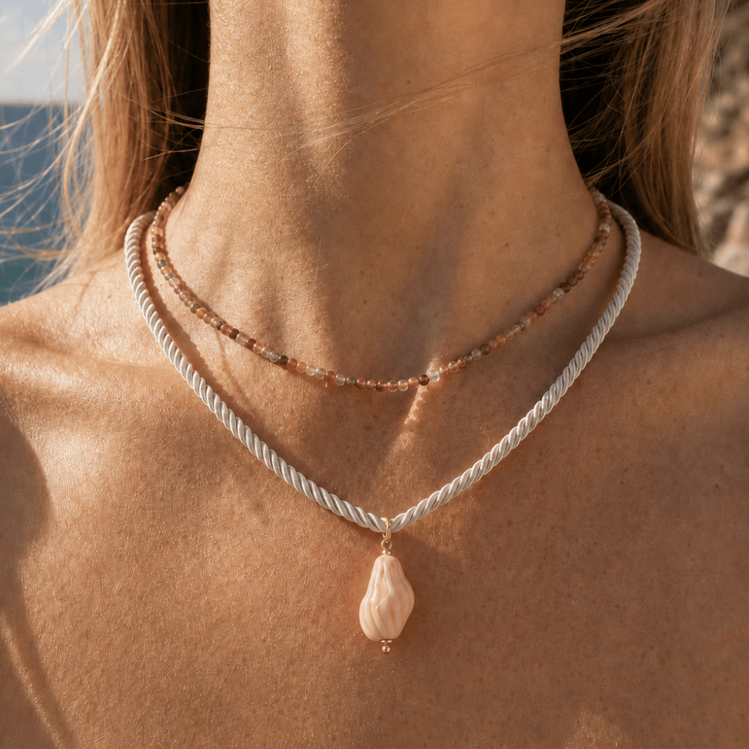 Model draagt wit koord met roze schelp hanger van Casa Jadel