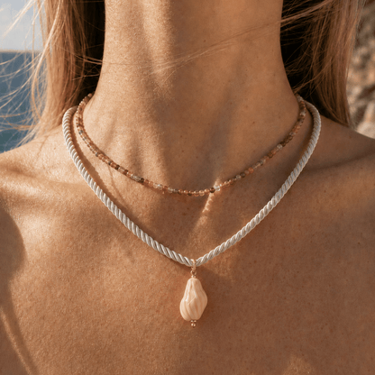 Model draagt wit koord met roze schelp hanger van Casa Jadel
