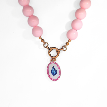 Wit-roze ovale bedel met handgeschilderde blauwe schelp aan een kralenketting met boeislot, Ibiza-style van Jadel.