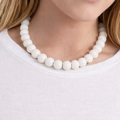 Witte kralenketting met ronde glanzende kralen gedragen op wit shirt – Casa Jadel