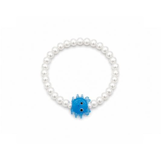 Witte parelarmband met een blauw glazen krabbetje van Casa Jadel op een witte achtergrond.
