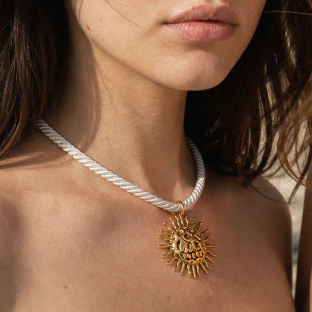 Model draagt witte rope ketting met grote gouden zon bedel van Casa Jadel
