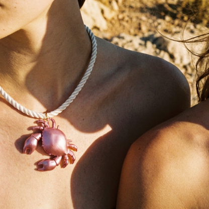 Model draagt witte rope ketting met roze krab bedel van Casa Jadel