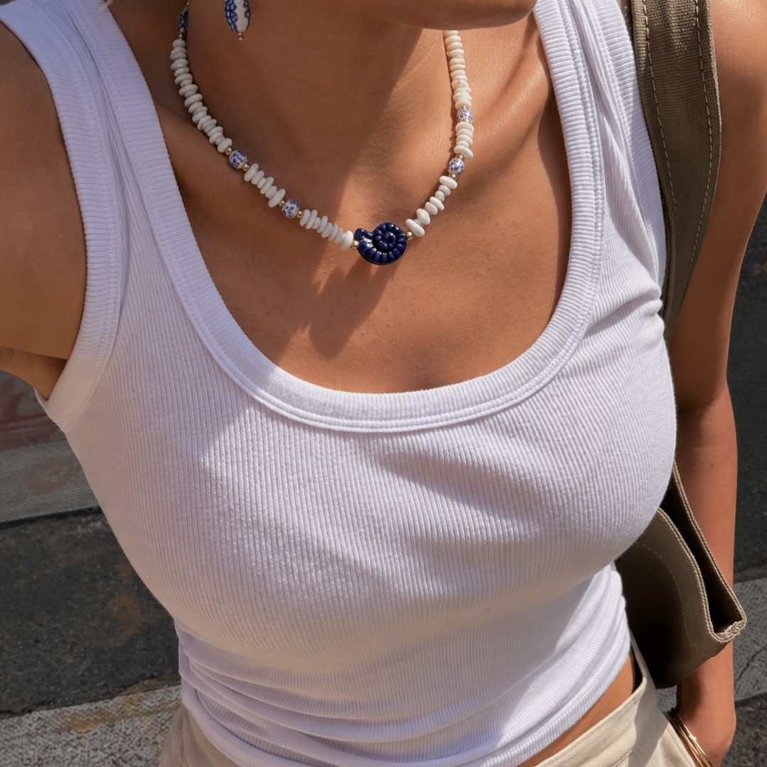 model met Witte schelpenketting met blauwe schelp bedel en goudkleurige details