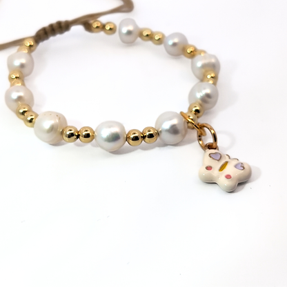 Witte vlinder bedel met paarse hartjes gedragen aan een kralenarmband, speelse Ibiza-style sieraden van Jadel.