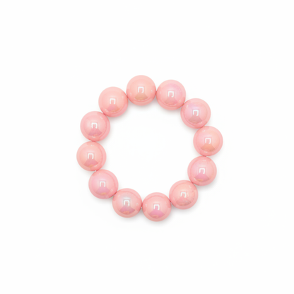Zachtroze chunky kralenarmband met grote glanzende kralen op lichte achtergrond schuin.