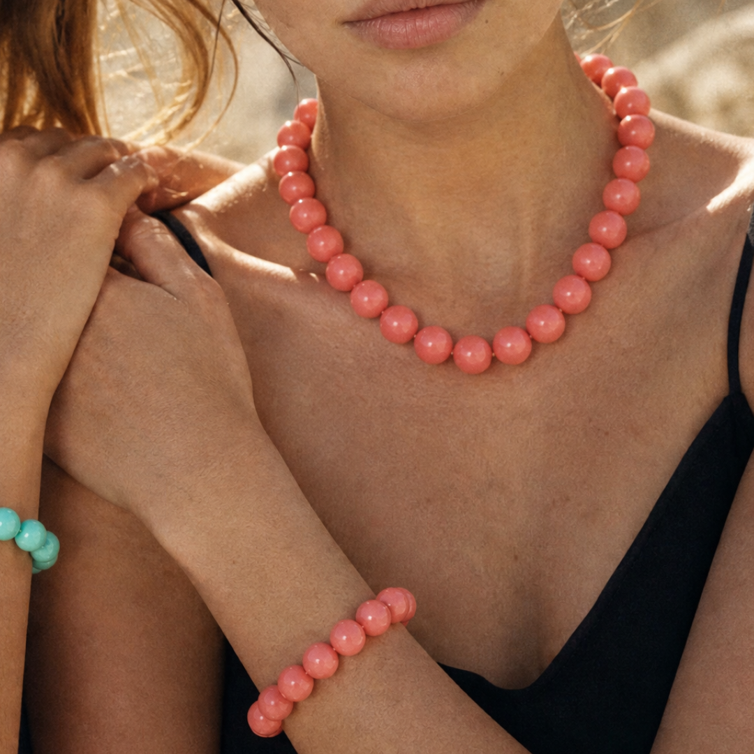 Modelt draagt grote kralenketting en kralenarmband in zalmroze van Casa Jadel. Ibiza Style