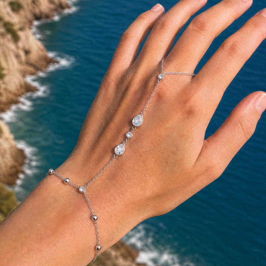 zilveren hand chain armband met ring en ovale steentjes verbonden met fijne schakels gedragen om hand en vinger