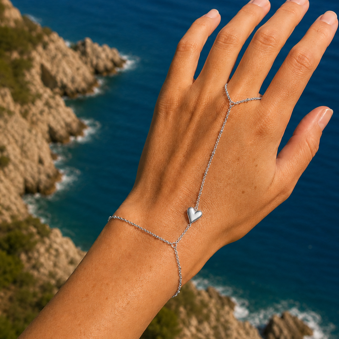 Zilveren hand chain met dubbele armband, ring en hartje gedragen bij de zee.