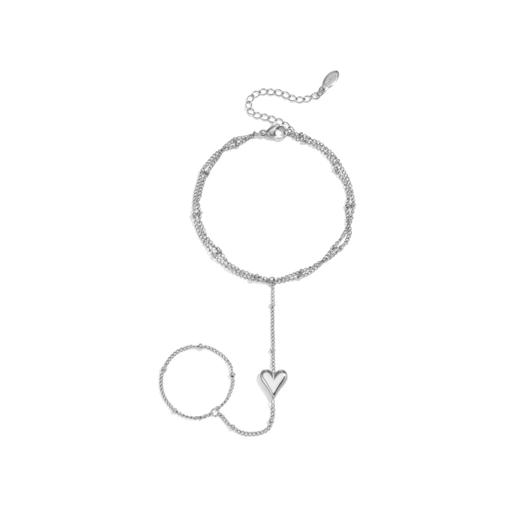 Zilveren handchain met dubbele armband, ring en hartje op witte achtergrond