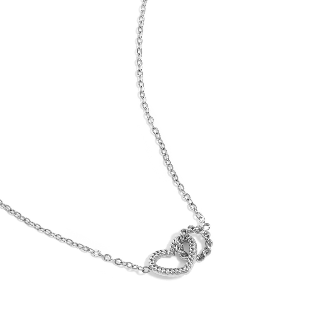 Fijne zilverkleurige ketting met een hartje en ringetje hanger op witte achtergrond.