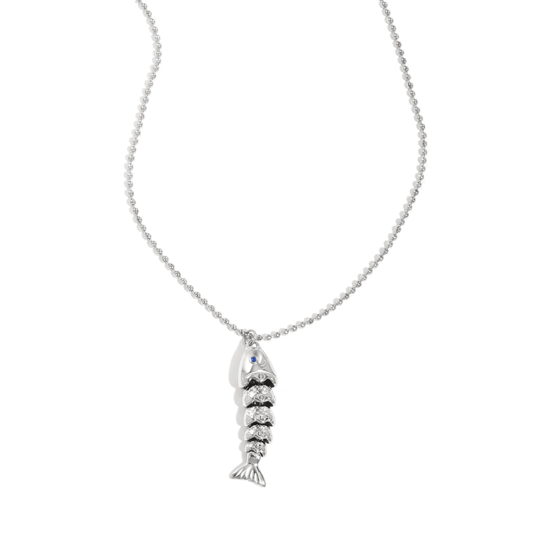 Zilveren ketting met gedetailleerde vis bedel aan fijne bolletjesketting op lichte achtergrond.