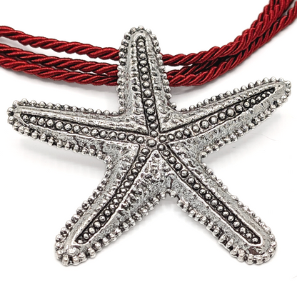 Close-up van grote zilveren zeester hanger aan rode rope ketting