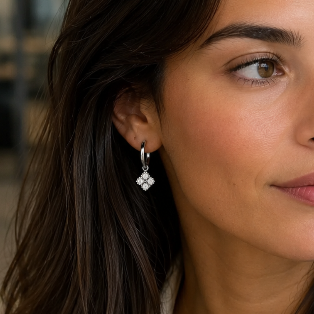 Model met zilverkleurige hoop oorbellen met klaver bedel en fonkelende strass steentjes