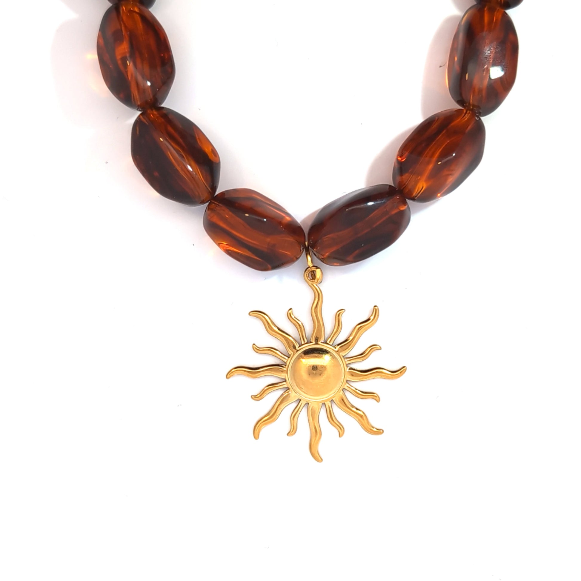 Goudkleurige zon hanger gedragen aan een amber kralenketting, zomerse styling van Jadel