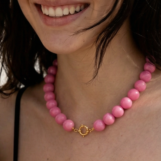 Model draagt grote kralenketting in zuurstok roze.