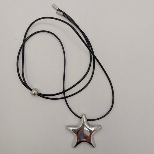 Zwart koord ketting met zilveren ster in een draai op grijze achtergrond