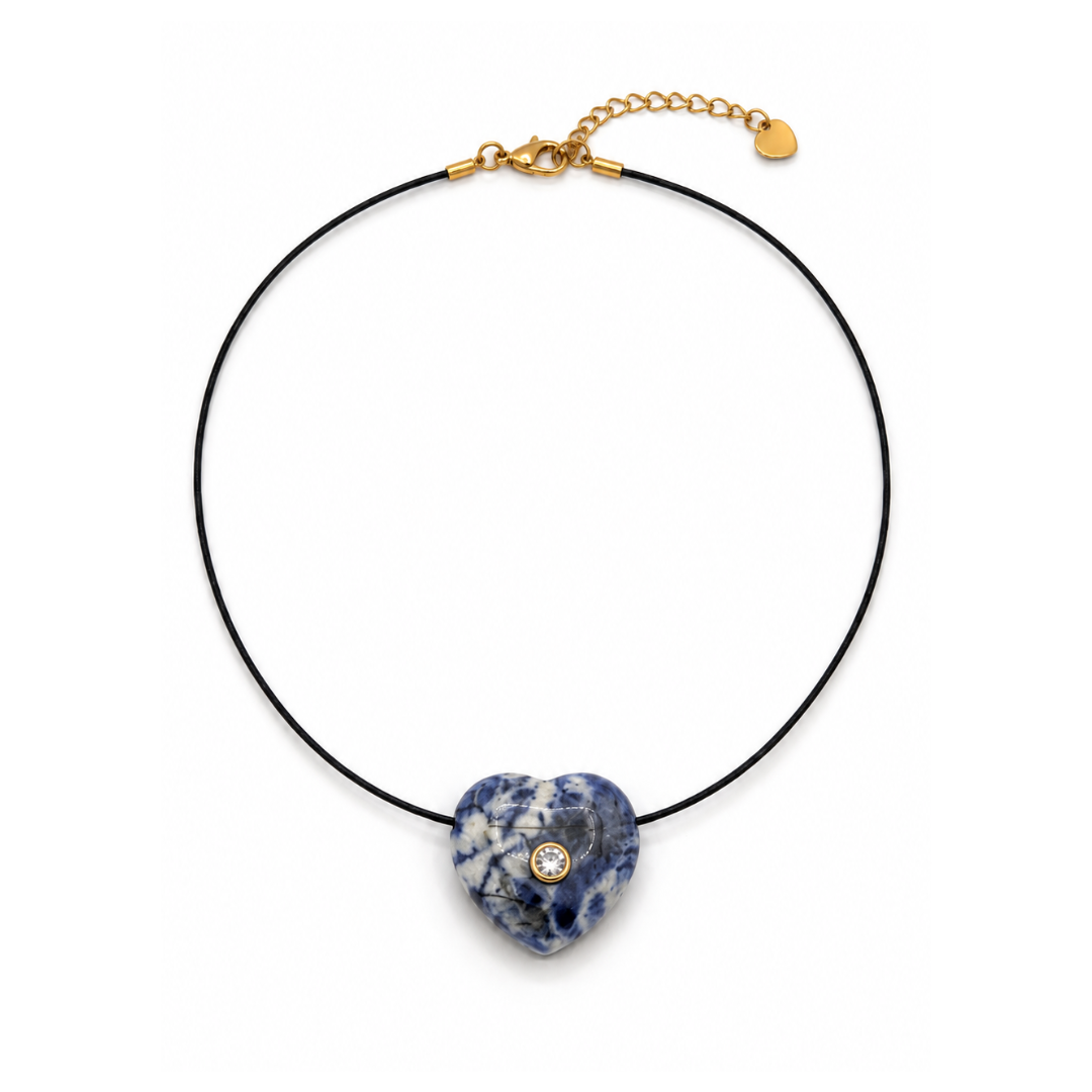 Zwarte koordketting met een bol sodaliet hartje in blauw met witte aders, een glinsterend steentje en een goudkleurige sluiting.
