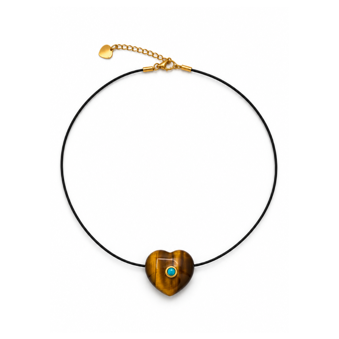 Zwarte koordketting met een bol tijgeroog hartje met turquoise steentje en een goudkleurige sluiting met hartjeslabel op een witte achtergrond.