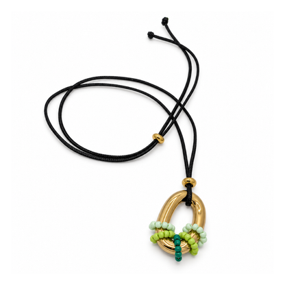 Zwarte lange koordketting met een goudkleurige ovale ringhanger, omwikkeld met kleine kralen in mintgroen, limegroen en diepgroen.